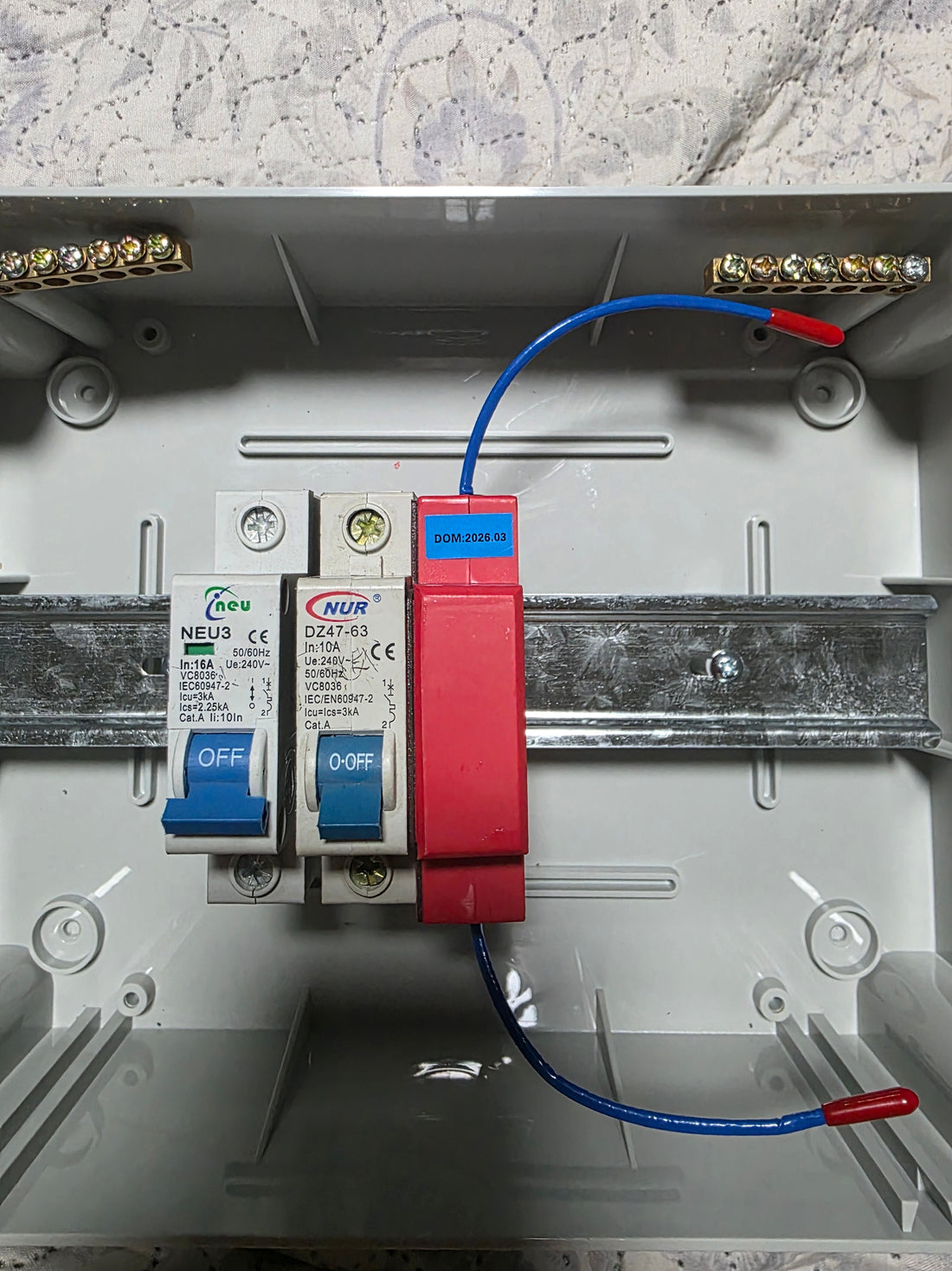 Fire Stickers Automatic Fire Extinguisher clipped onto DIN rail inside an open DB box with blue thermal cord visible